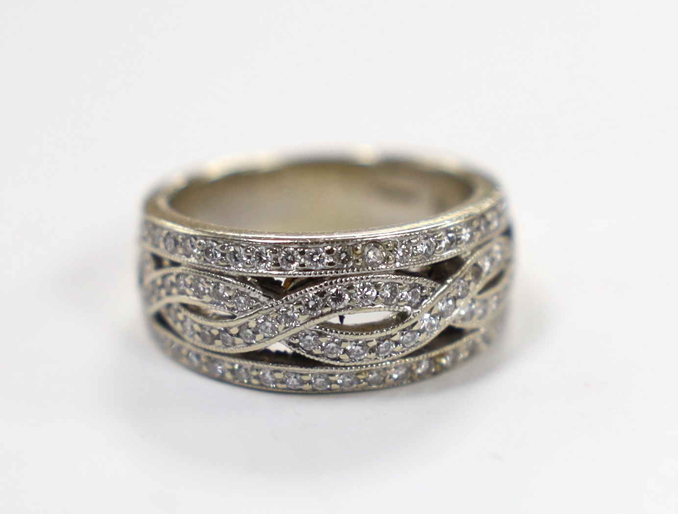 A modern 14ct white gold and diamond chip set spiral cluster ring with diamond set borders, size L, gross weight 7.2 grams.